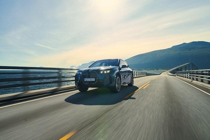 simple BMW iX run away at road with beautiful mountain background